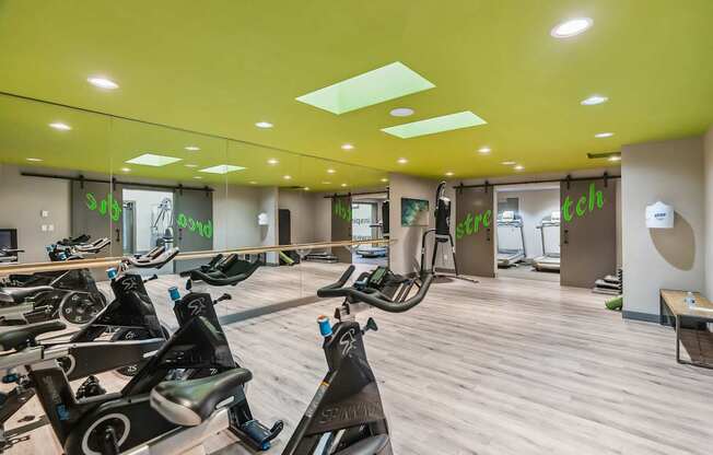 A gym with a row of stationary bikes.
