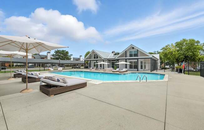A large outdoor swimming pool with sun loungers and umbrellas.
