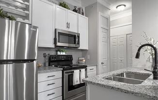A modern kitchen with a stainless steel refrigerator, microwave, and oven.