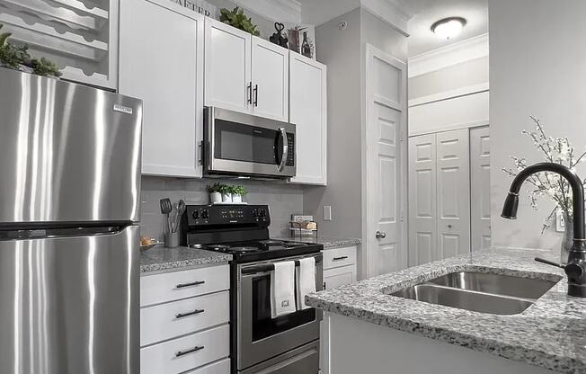 A modern kitchen with a stainless steel refrigerator, microwave, and oven.