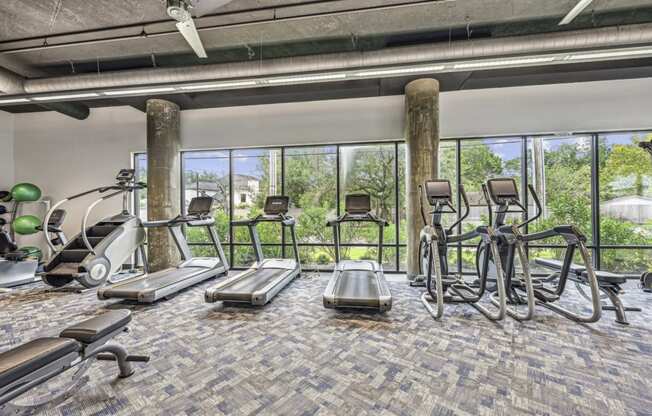 Fitness center with treadmills, elliptical machines, and a stair climber at Allusion at West University apartments in Houston, TX