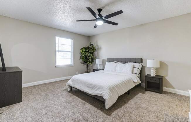 an empty bedroom with a bed and a ceiling fan