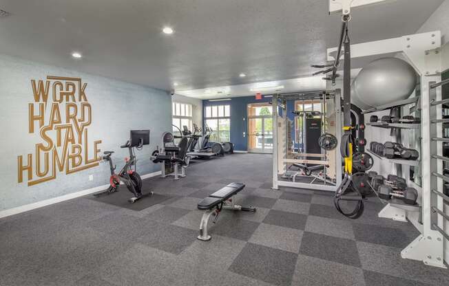 A gym with a variety of equipment including a rowing machine, a bench, and a weight rack.