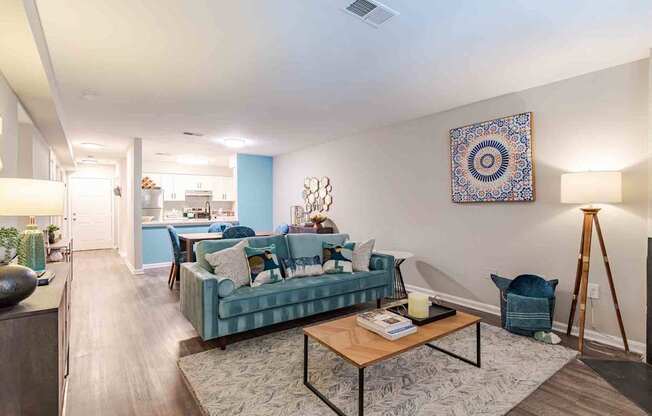 A living room with a blue couch and a rug.