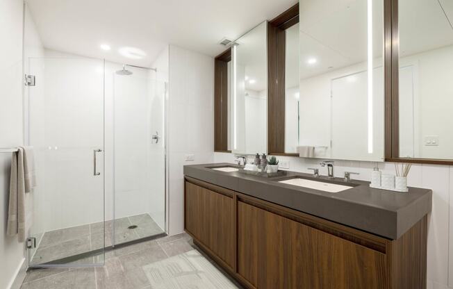 a bathroom with a large vanity with two sinks and a walk in shower