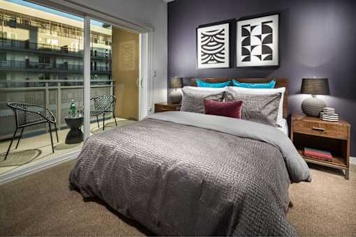 A bedroom with a large bed and a chair by the window.