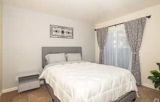 a bedroom with a white bedspread and gray headboard