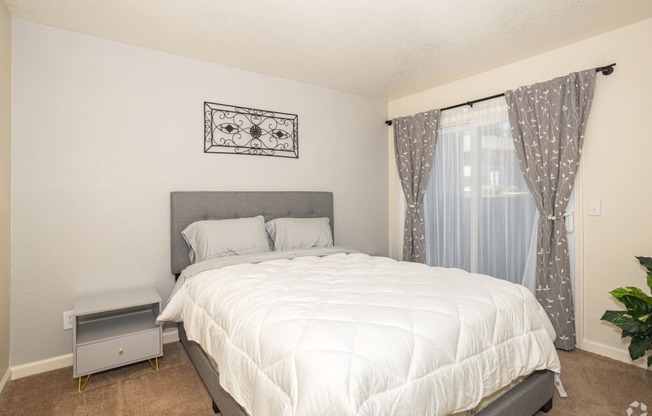 a bedroom with a white bedspread and gray headboard