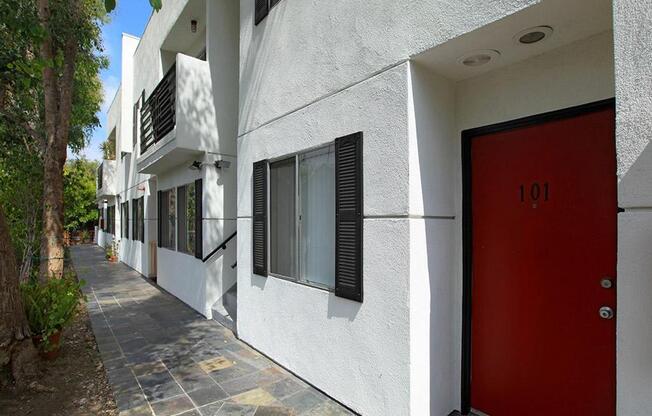 entrance to a unit with a red door and a walkway