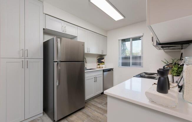 a kitchen with white cabinets and a stainless steel refrigerator