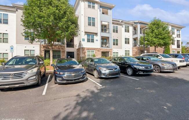 a parking lot full of cars in front of an apartment building