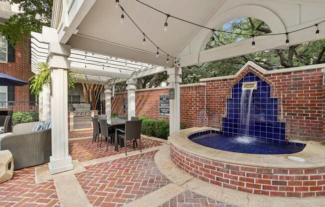 A patio with a fountain and a table set for dining.
