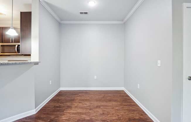 an empty room with a wood floor and a kitchen