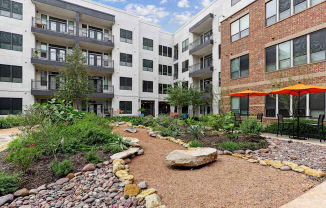 A courtyard with a gravel path and a large rock in the middle.