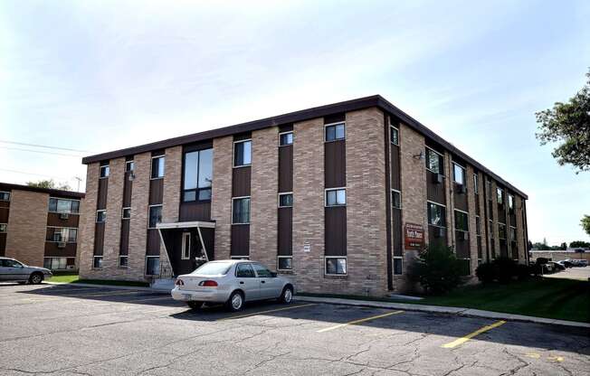 a brick apartment building with a car parked outside. Fargo, ND North Manor Apartments