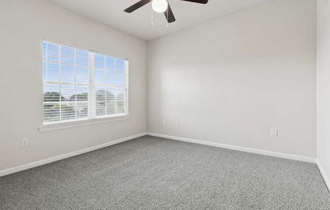 A room with a ceiling fan and a window with blinds.