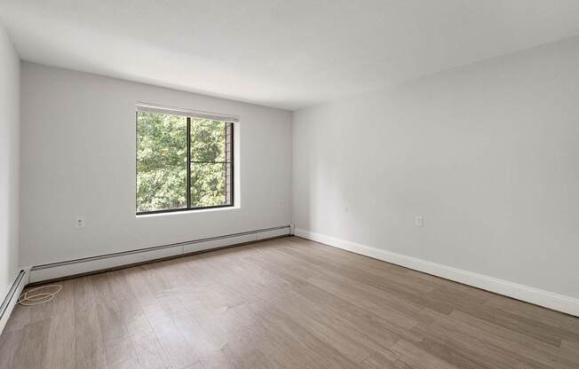 A room with a window and wooden flooring.