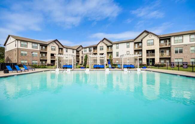 A large swimming pool in front of apartment buildings.