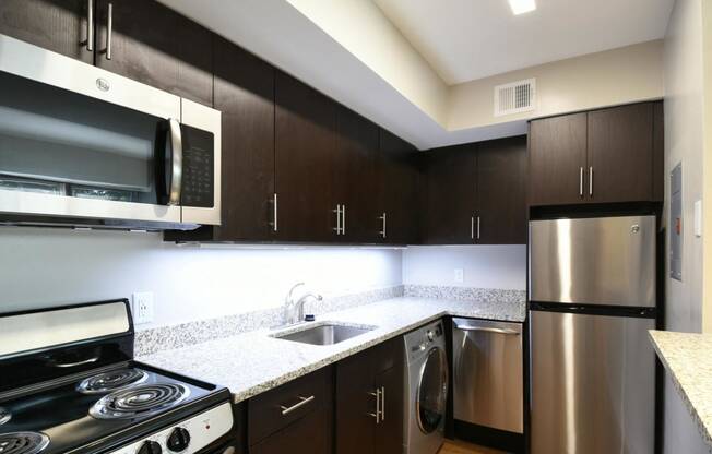 a kitchen with dark cabinets and stainless steel appliances