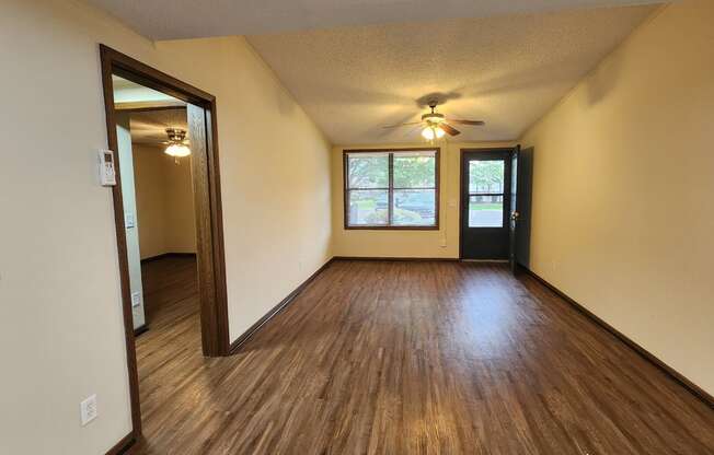 the living room of an empty house with wooden floors and a ceiling fan
