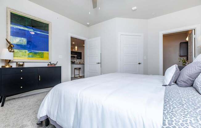 A bedroom with a large bed and a painting on the wall.