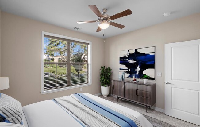 a bedroom with a large window and a ceiling fan