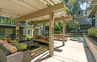 a covered patio with furniture and a wooden pergola