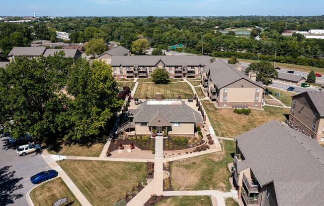 An aerial view of Olde English Village Apartments, nestled among the serene landscape, featuring a cluster of well-maintained buildings with courtyards and walkways.