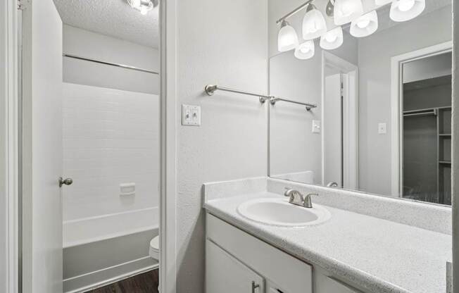 A bathroom with a sink, mirror, and shower.