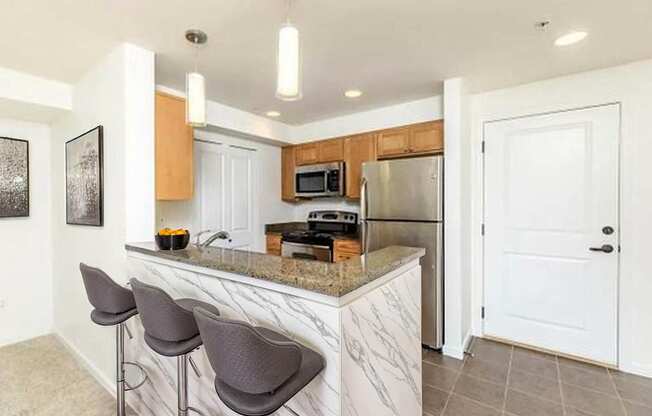 A kitchen with a marble countertop and bar stools.