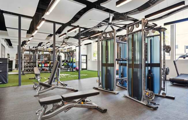 a spacious fitness center with benches at apartment community