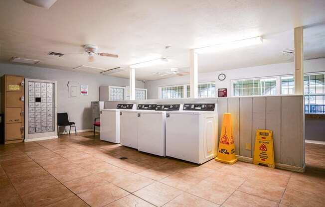 a laundry room with four washing machines and a yellow caution sign