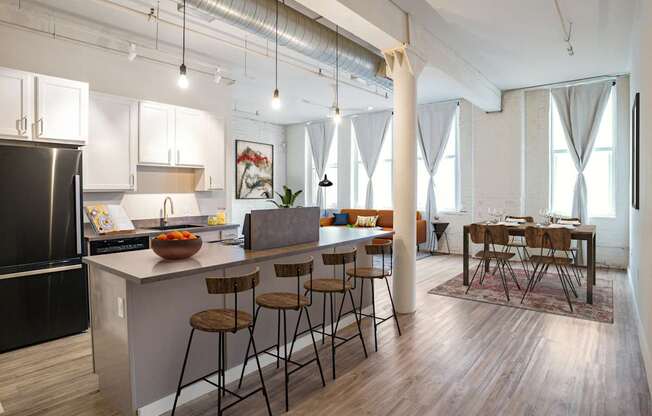 A kitchen with a black refrigerator and wooden floors.