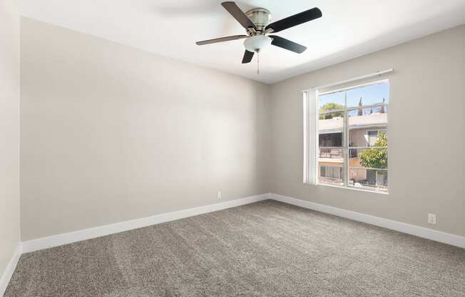 an empty room with a ceiling fan and a window