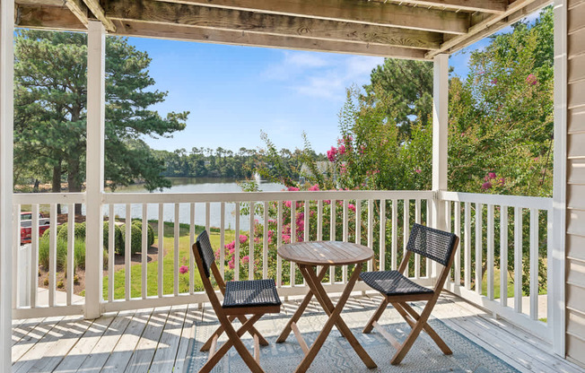 A wooden table and two chairs are on a porch.