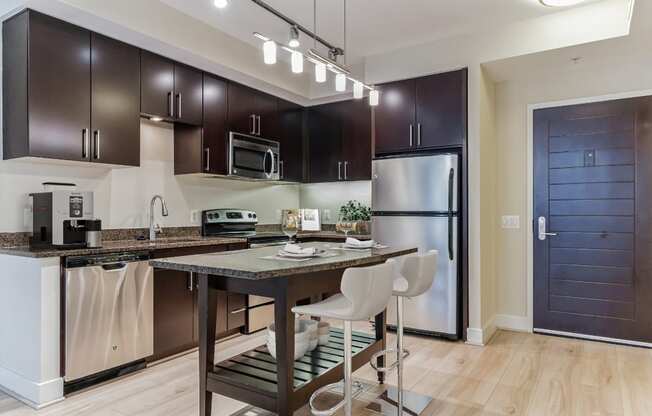 a kitchen with stainless steel appliances and a bar with chairs