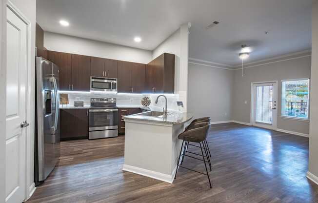 a kitchen with stainless steel appliances and a island with two chairs