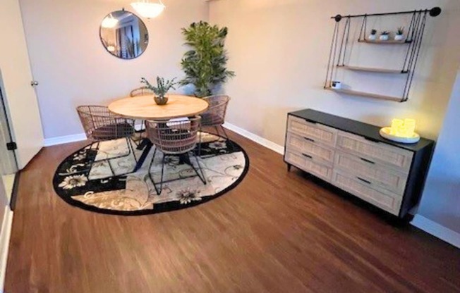 A room with a round table and chairs in the middle of a rug.