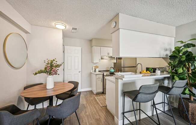 A kitchen with a table and chairs in front of it.