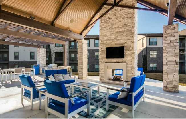 a covered patio with blue chairs and a fireplace at The McKenzie Park Apartments, Little Rock, Arkansas