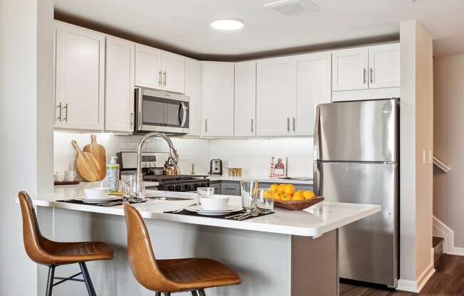 a kitchen with white cabinets and stainless steel appliances at Metro 303, Hempstead, NY