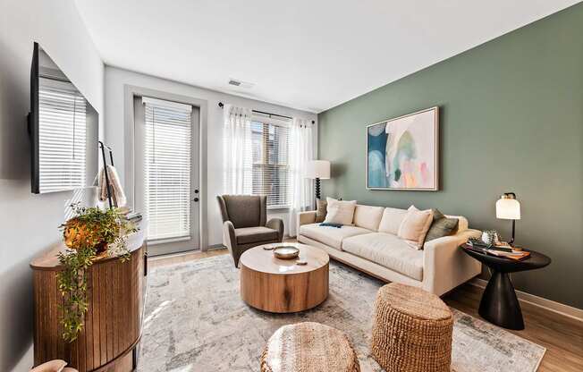 A living room with a white sofa, a wooden coffee table, and a TV on the wall