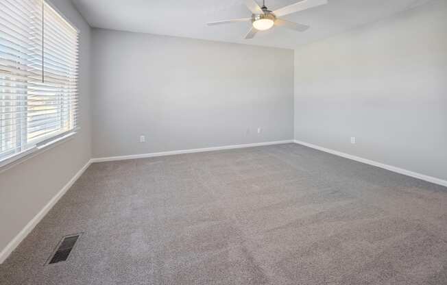 an empty living room with a ceiling fan and a window