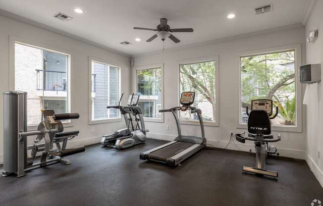 A spacious home gym with a treadmill, elliptical machines, and a stationary bike.
