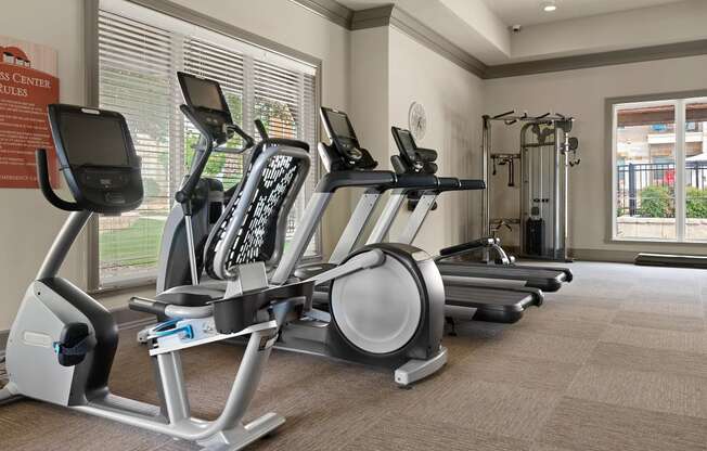 a gym with cardio equipment and a lot of windows