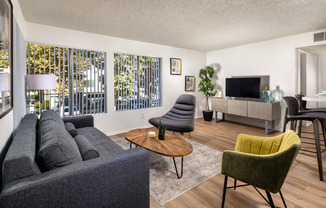 A living room with a grey couch, a green chair, and a wooden coffee table.