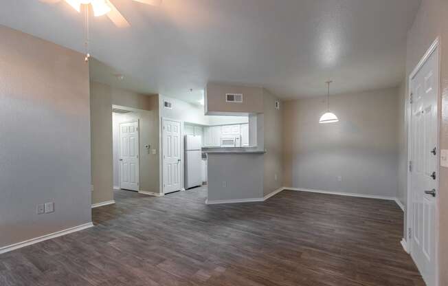 an empty living room and kitchen with wood flooring