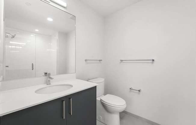 A white bathroom with a toilet, sink, and mirror.