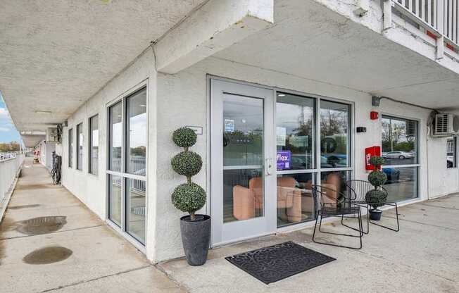 A white building with a balcony has a black mat on the floor.