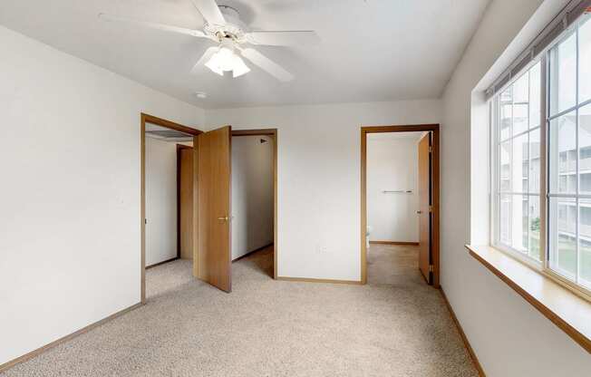 an empty room with three doors and a ceiling fan